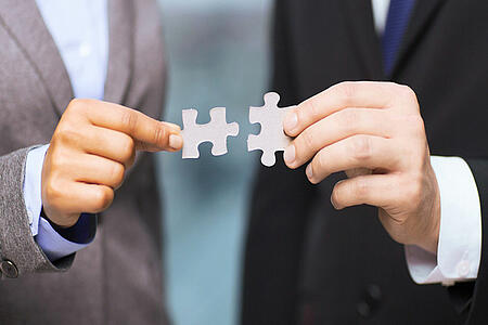 News Partnership AFI and avvaneo Partial view of two men in suits Two puzzle pieces in their hands